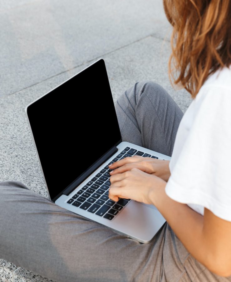 Side view of a young woman typing on laptop computer